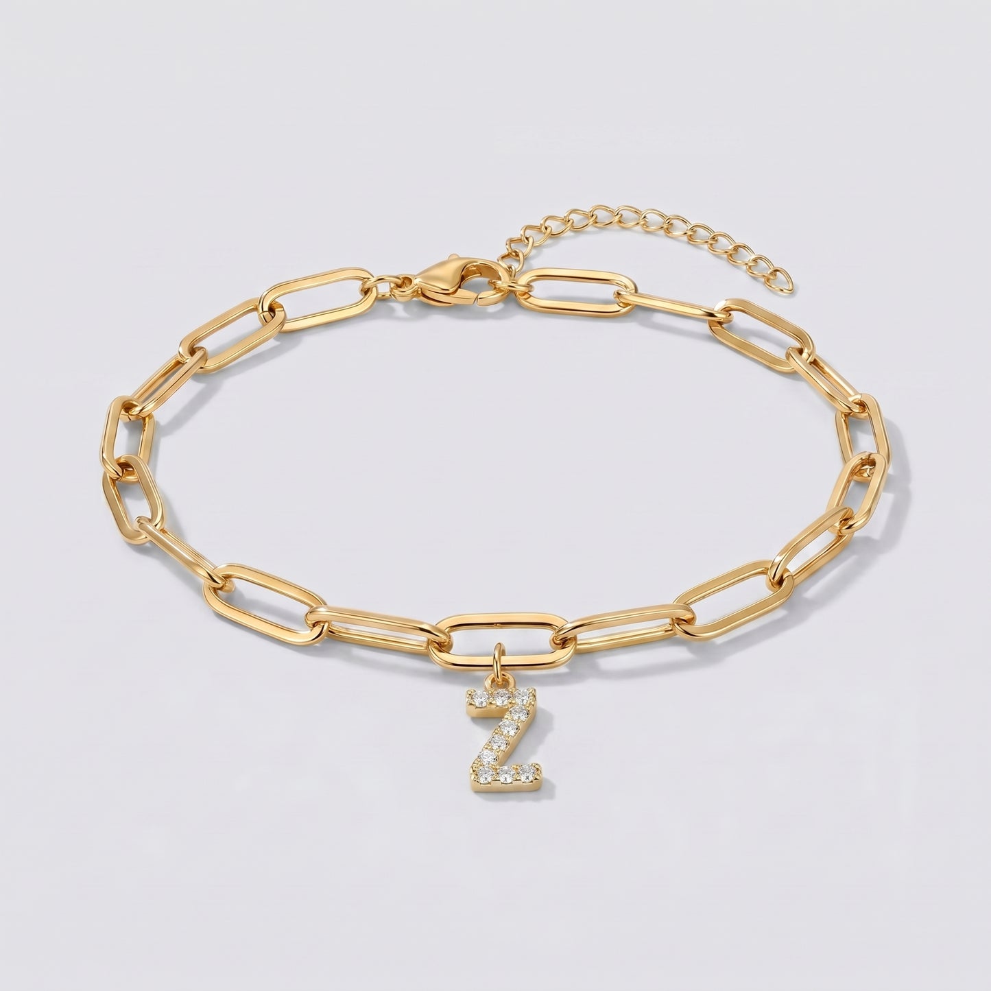 Pulseira dourada com letra inicial Z, corrente paperclip e pendente de letra cravejado.