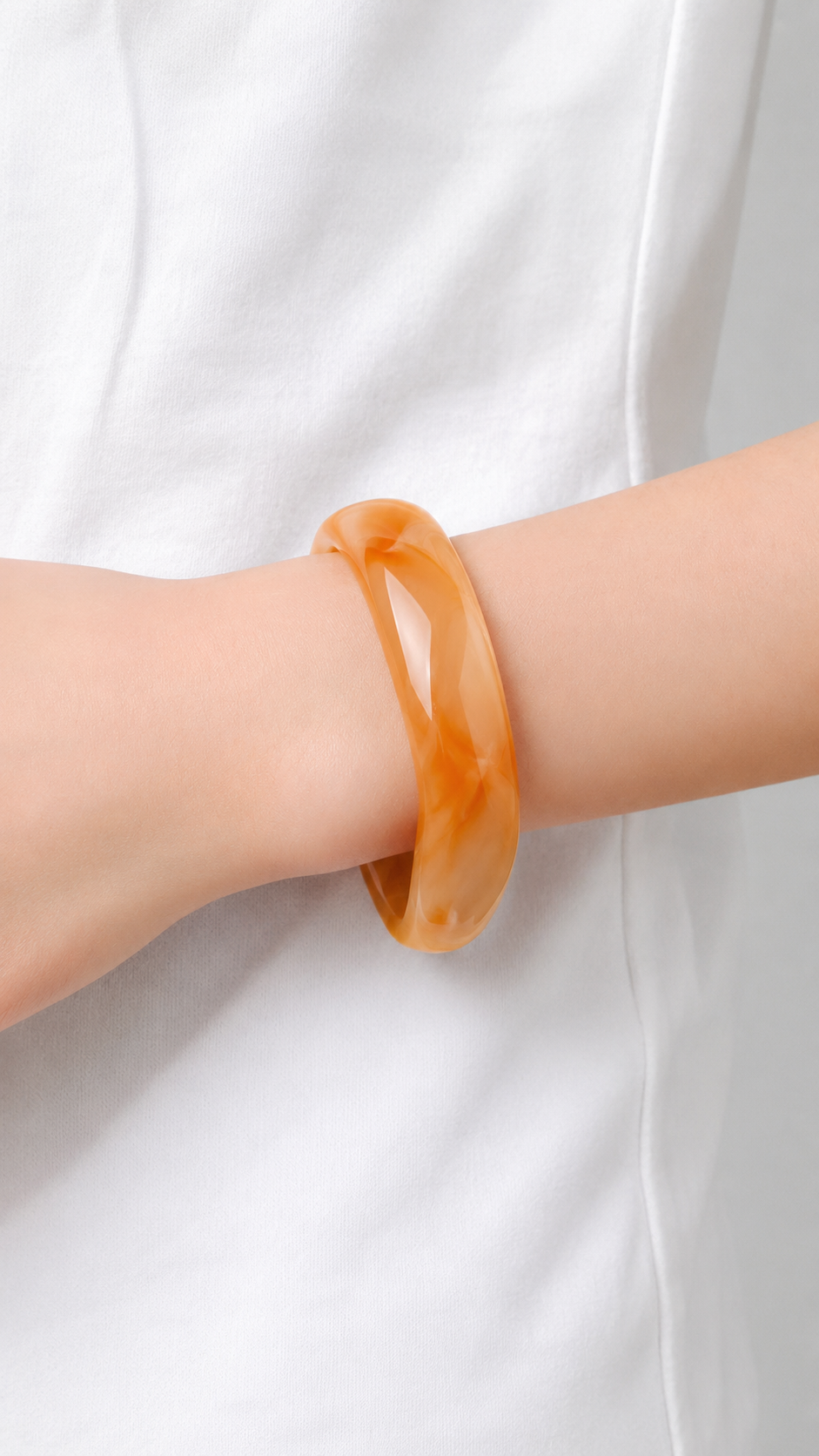 Pulseira de resina laranja marmoreada usada no pulso, com acabamento brilhante e estilo elegante.