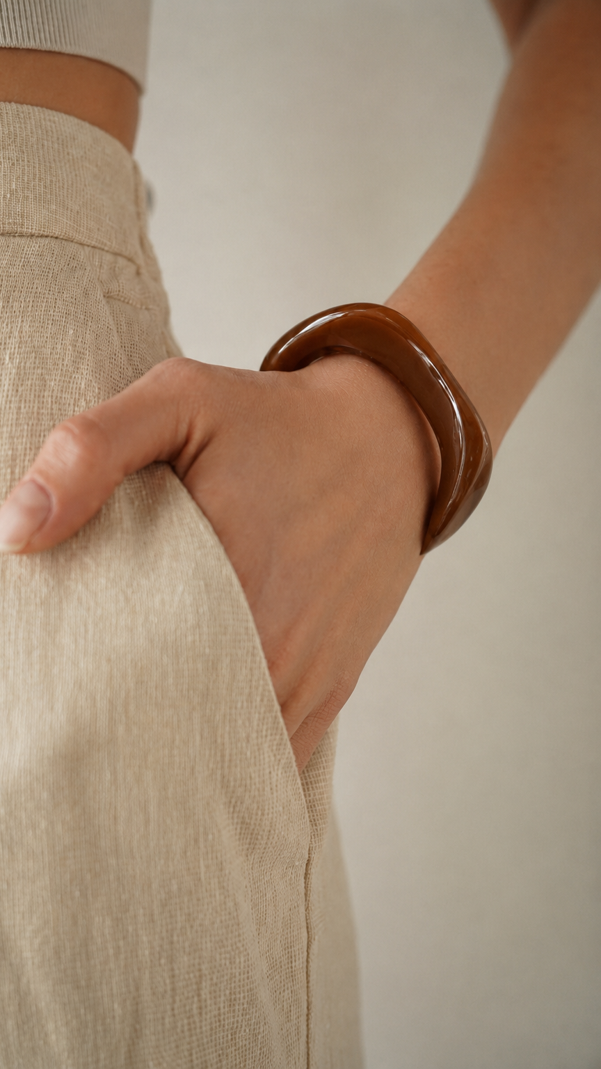 Pulseira de resina castanha usada no pulso, com acabamento brilhante e estilo elegante.