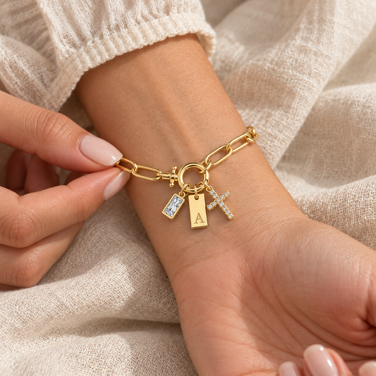 Pulseira dourada com inicial A e cruz no pulso