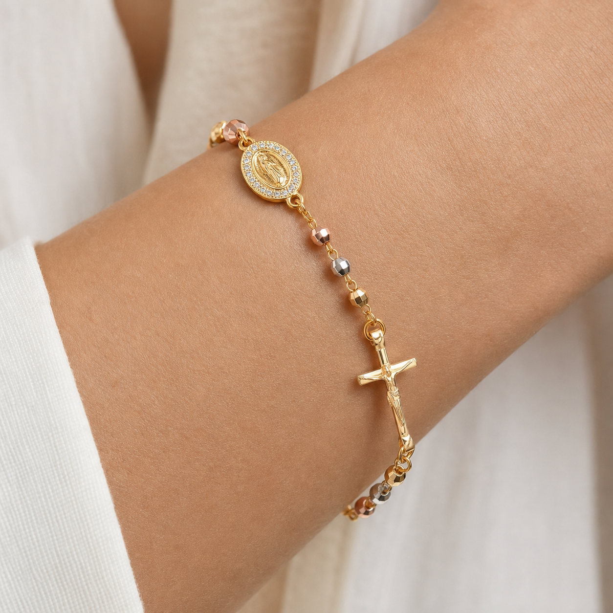 Mulher a usar a Pulseira Ave Maria no pulso — medalha da Virgem, crucifixo e contas tricolor.