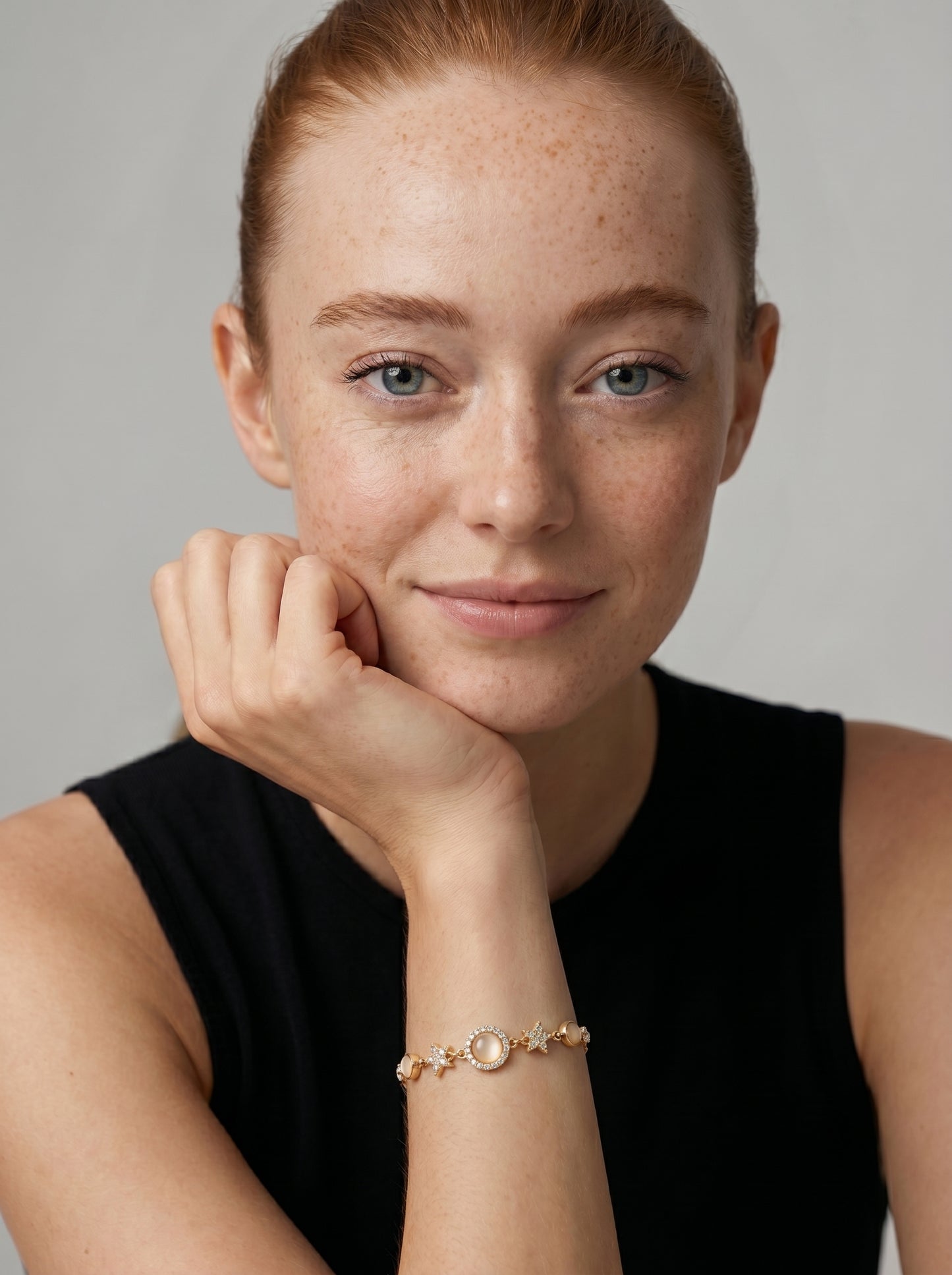 Pulseira dourada delicada com cristais brilhantes, detalhes em estrela e pendente circular central, usada por uma modelo para um visual elegante, feminino e sofisticado.