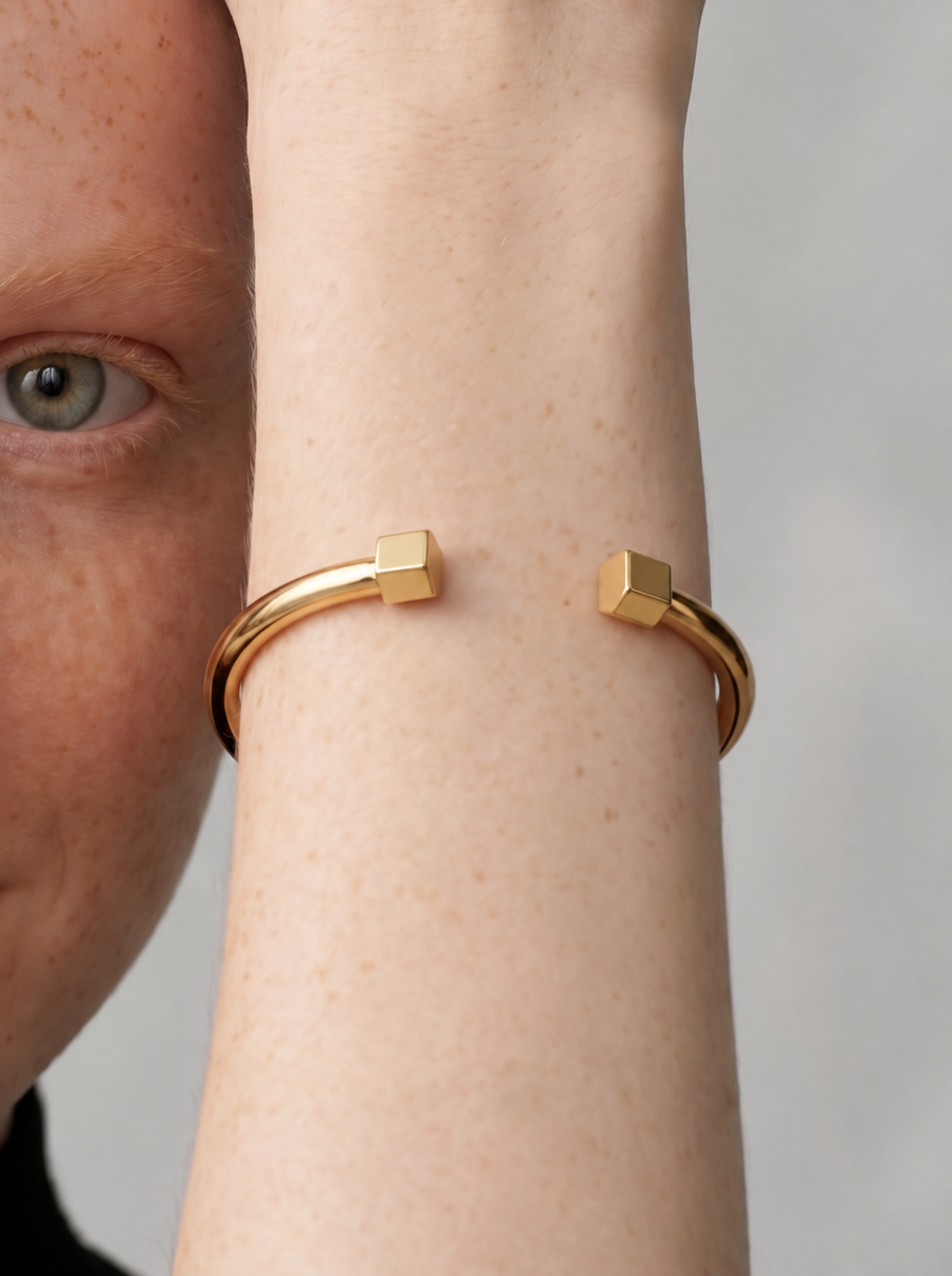 Pulseira Cuff Geométrica dourada — no pulso com terminações cúbicas