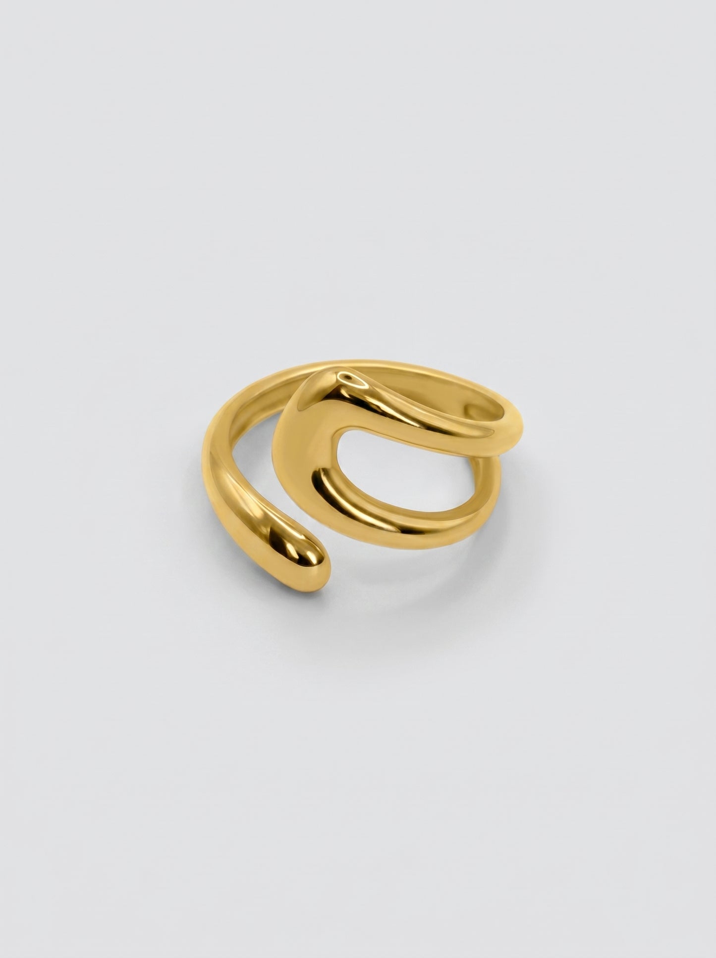 Anel dourado ajustável em formato fluido e moderno, com superfície polida e design aberto sobre fundo neutro.
