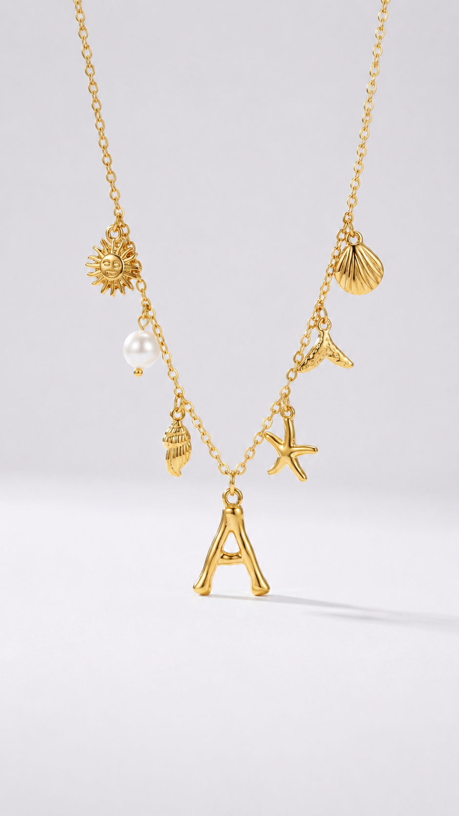 Colar dourado do mar com letra inicial A, estrela-do-mar, conchas, pérola e pendente de sol.