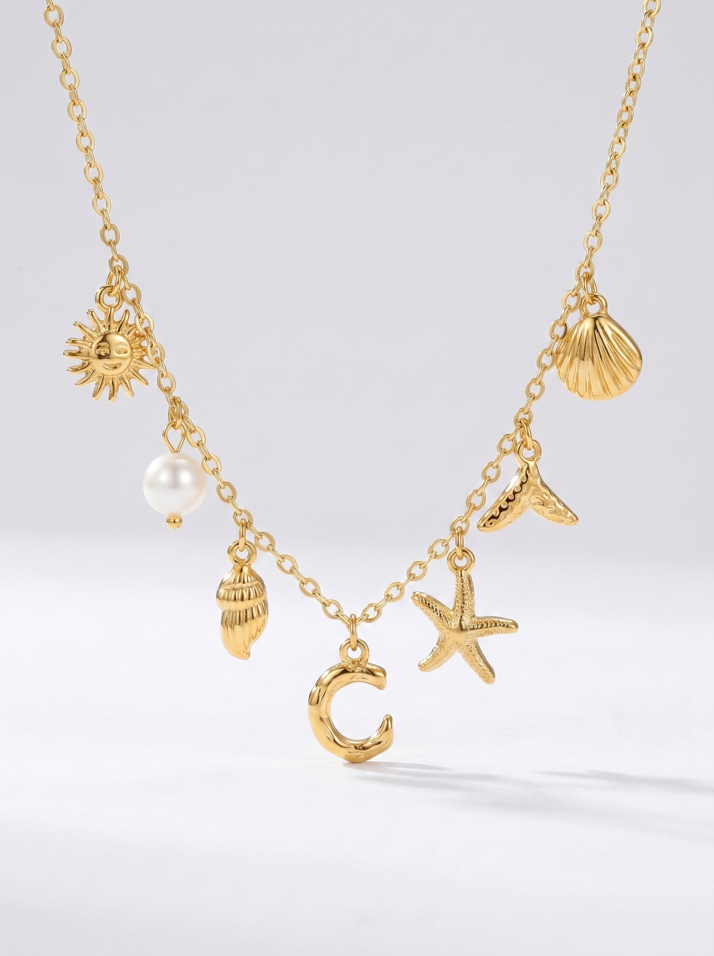 Colar dourado do mar com letra inicial C, estrela-do-mar, conchas, pérola e pendente de sol.