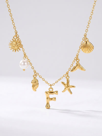 Colar dourado do mar com letra inicial F, estrela-do-mar, conchas, pérola e pendente de sol.