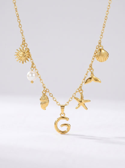 Colar dourado do mar com letra inicial G, estrela-do-mar, conchas, pérola e pendente de sol.
