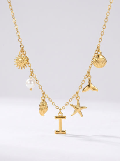 Colar dourado do mar com letra inicial I, estrela-do-mar, conchas, pérola e pendente de sol.