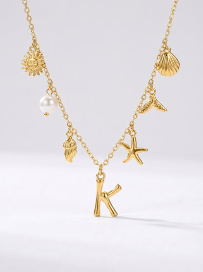 Colar dourado do mar com letra inicial K, estrela-do-mar, conchas, pérola e pendente de sol.