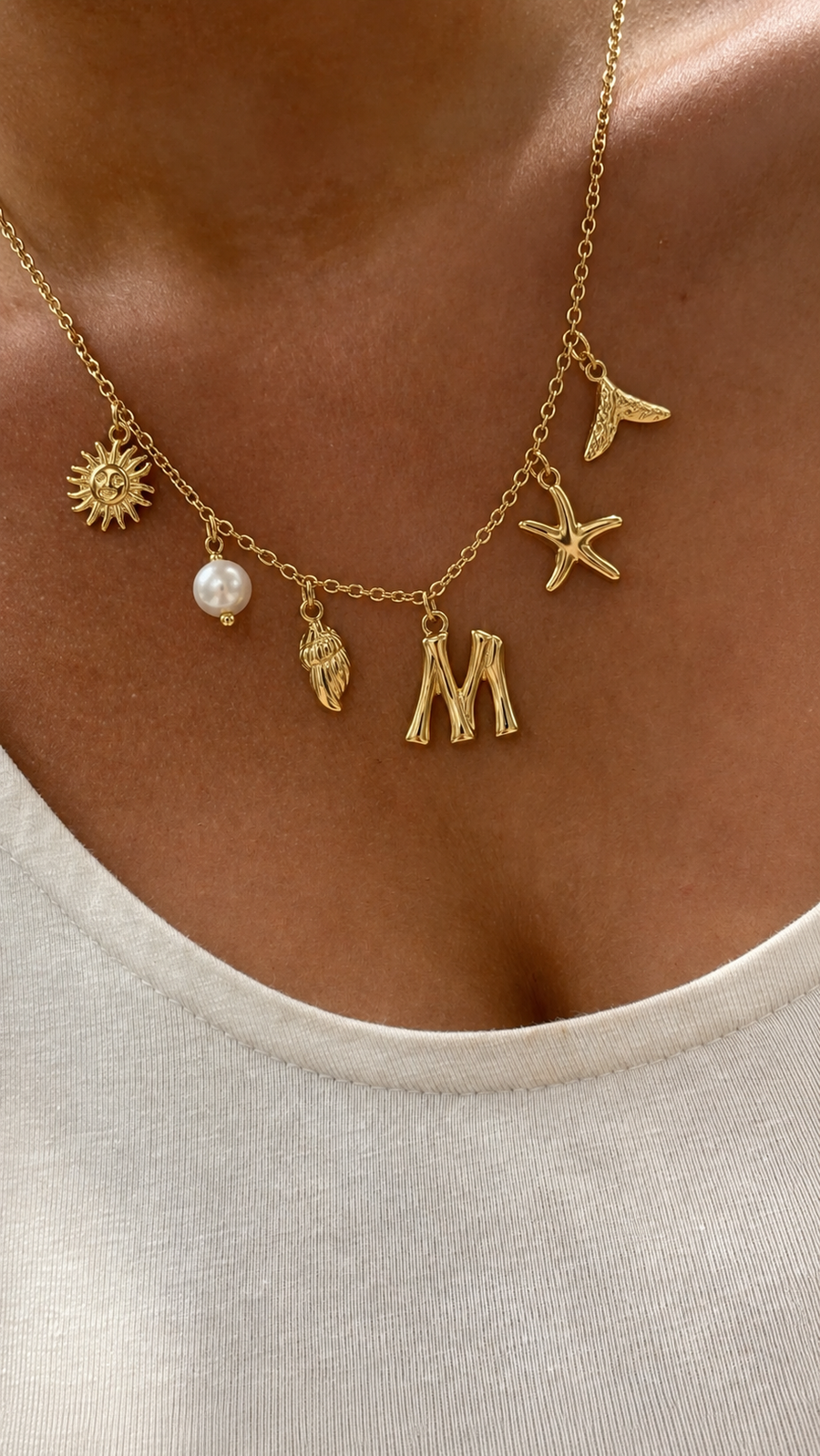 Colar dourado do mar com letra inicial M, estrela-do-mar, concha, pérola e pendentes delicados.