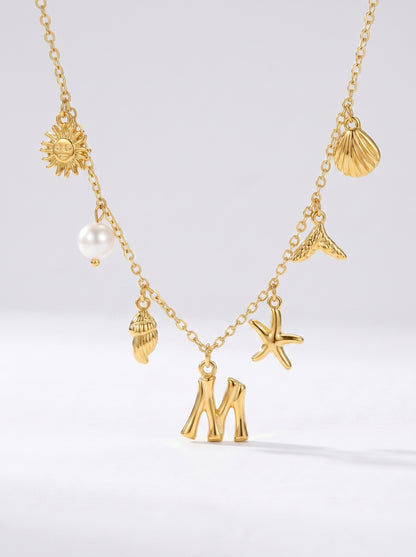 Colar dourado do mar com letra inicial M, estrela-do-mar, conchas, pérola e pendente de sol.