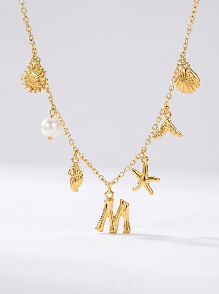 Colar dourado do mar com letra inicial M, estrela-do-mar, conchas, pérola e pendente de sol.