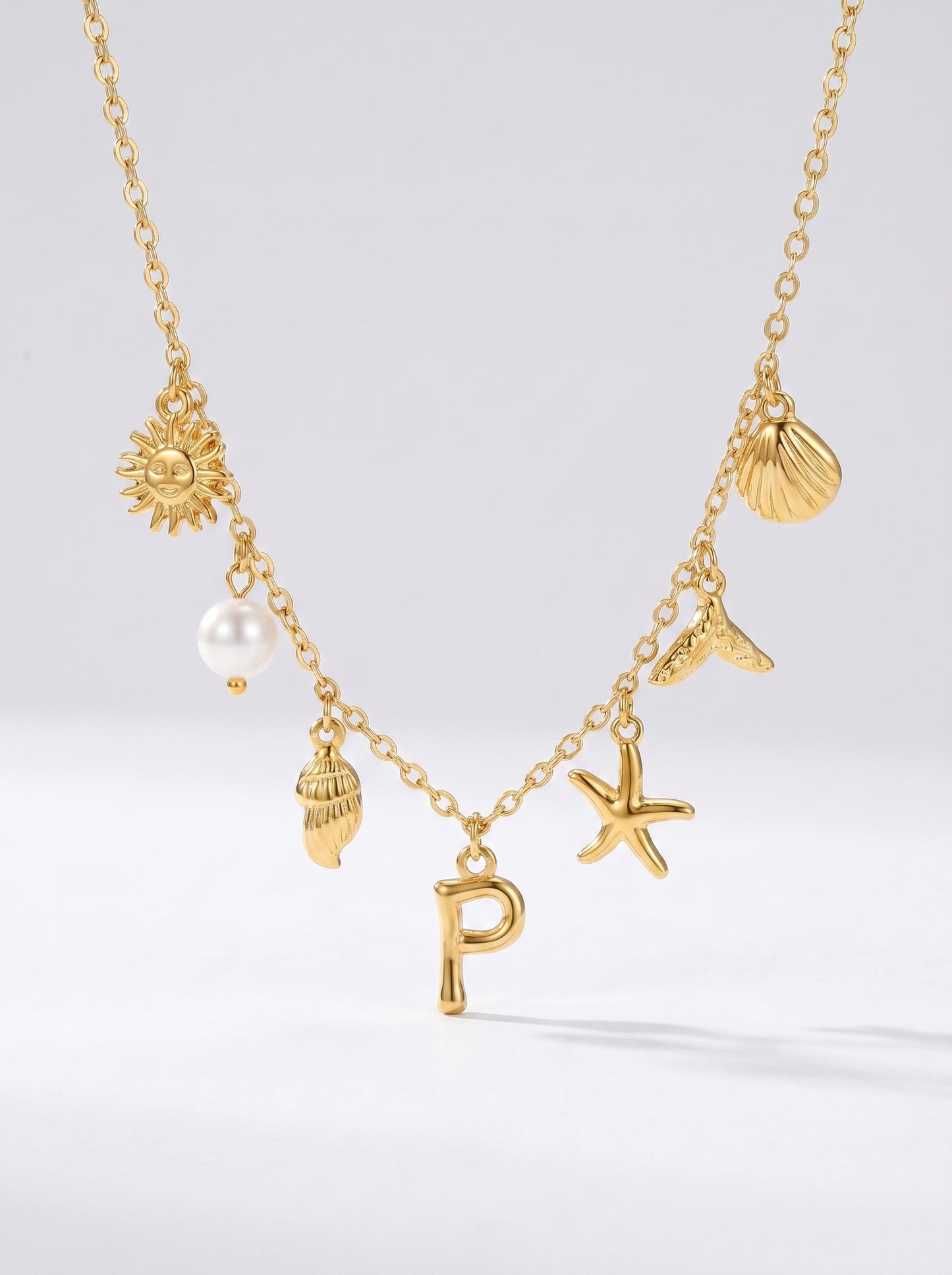 Colar dourado do mar com letra inicial P, estrela-do-mar, conchas, pérola e pendente de sol.