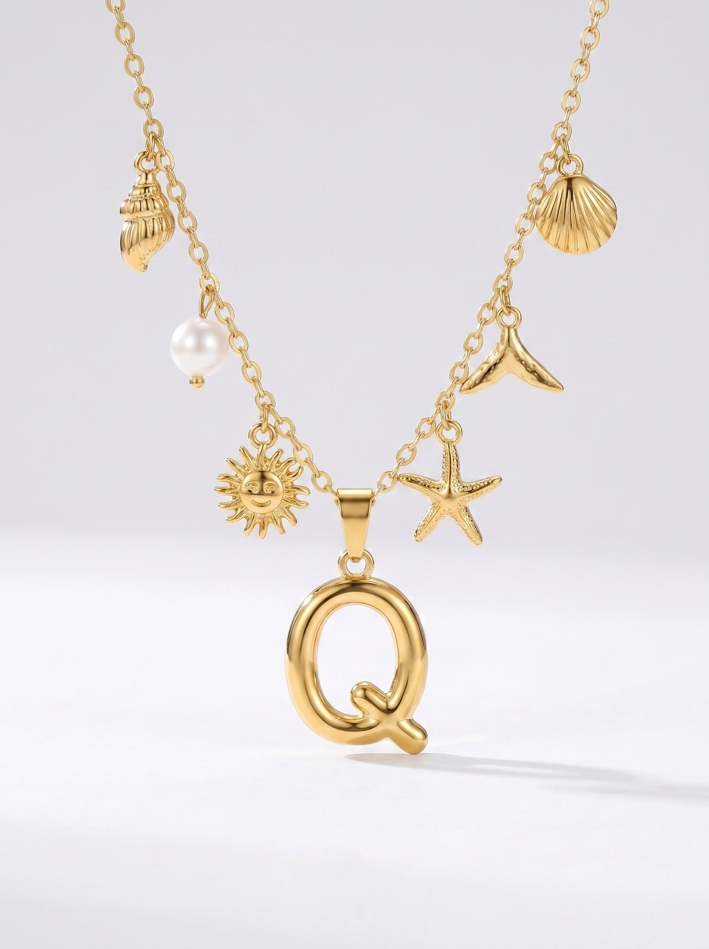 Colar dourado do mar com letra inicial Q, estrela-do-mar, conchas, pérola e pendente de sol.