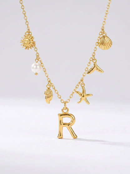Colar dourado do mar com letra inicial R, estrela-do-mar, conchas, pérola e pendente de sol.