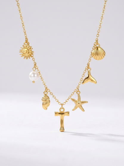 Colar dourado do mar com letra inicial T, estrela-do-mar, conchas, pérola e pendente de sol.