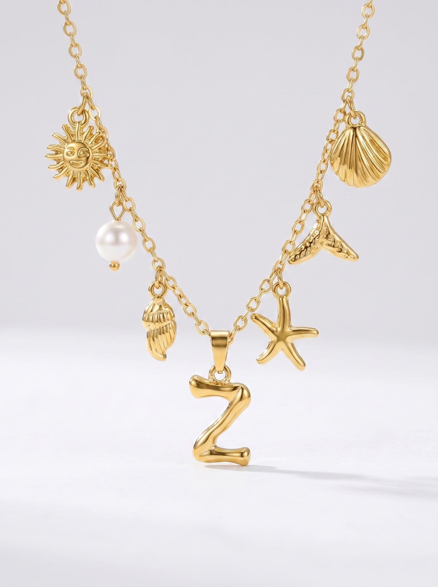 Colar dourado do mar com letra inicial Z, estrela-do-mar, conchas, pérola e pendente de sol.
