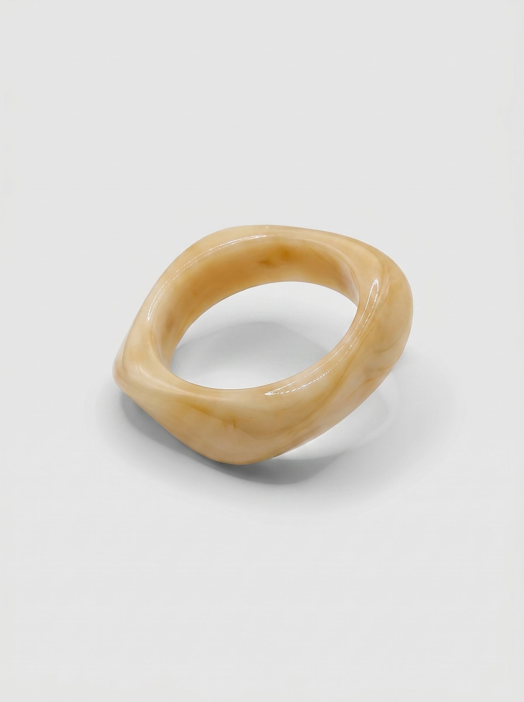Pulseira Baunilha em resina marmoreada nos tons baunilha e creme, com design orgânico geométrico e acabamento brilhante, ideal para um look elegante e contemporâneo.
