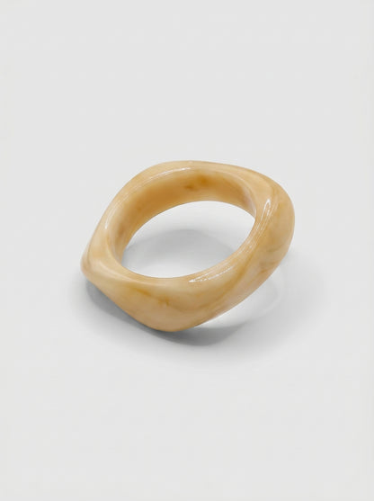 Pulseira Baunilha em resina marmoreada nos tons baunilha e creme, com design orgânico geométrico e acabamento brilhante, ideal para um look elegante e contemporâneo.
