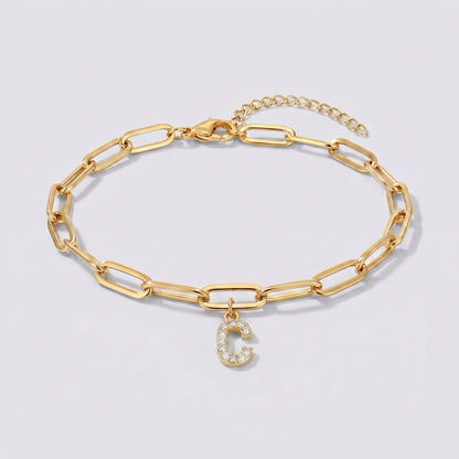Pulseira dourada com letra inicial C, corrente paperclip e pendente de letra cravejado.