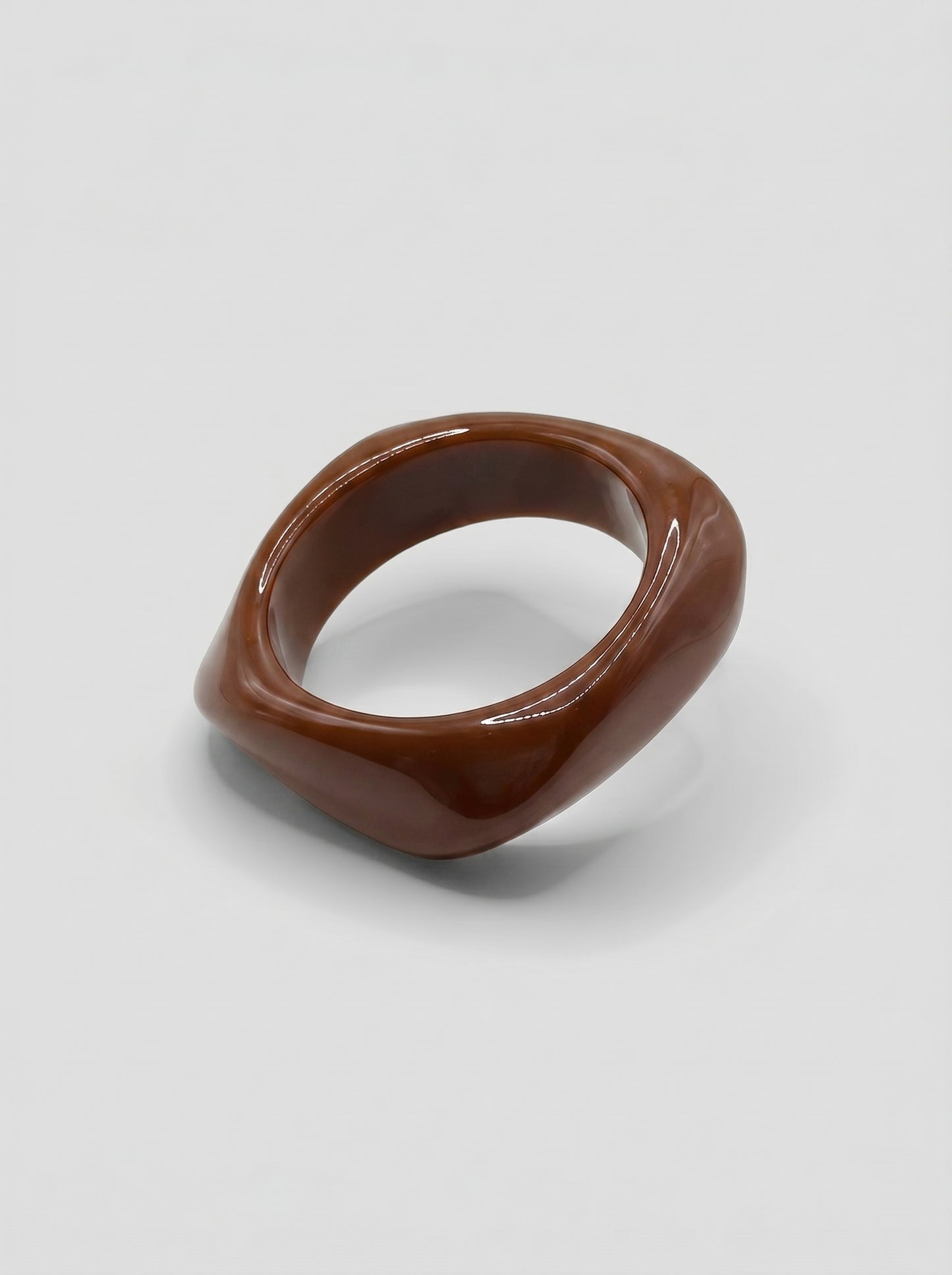 Pulseira Café em resina marmoreada nos tons café e castanho, com design orgânico geométrico e acabamento brilhante, ideal para um look elegante e contemporâneo.
