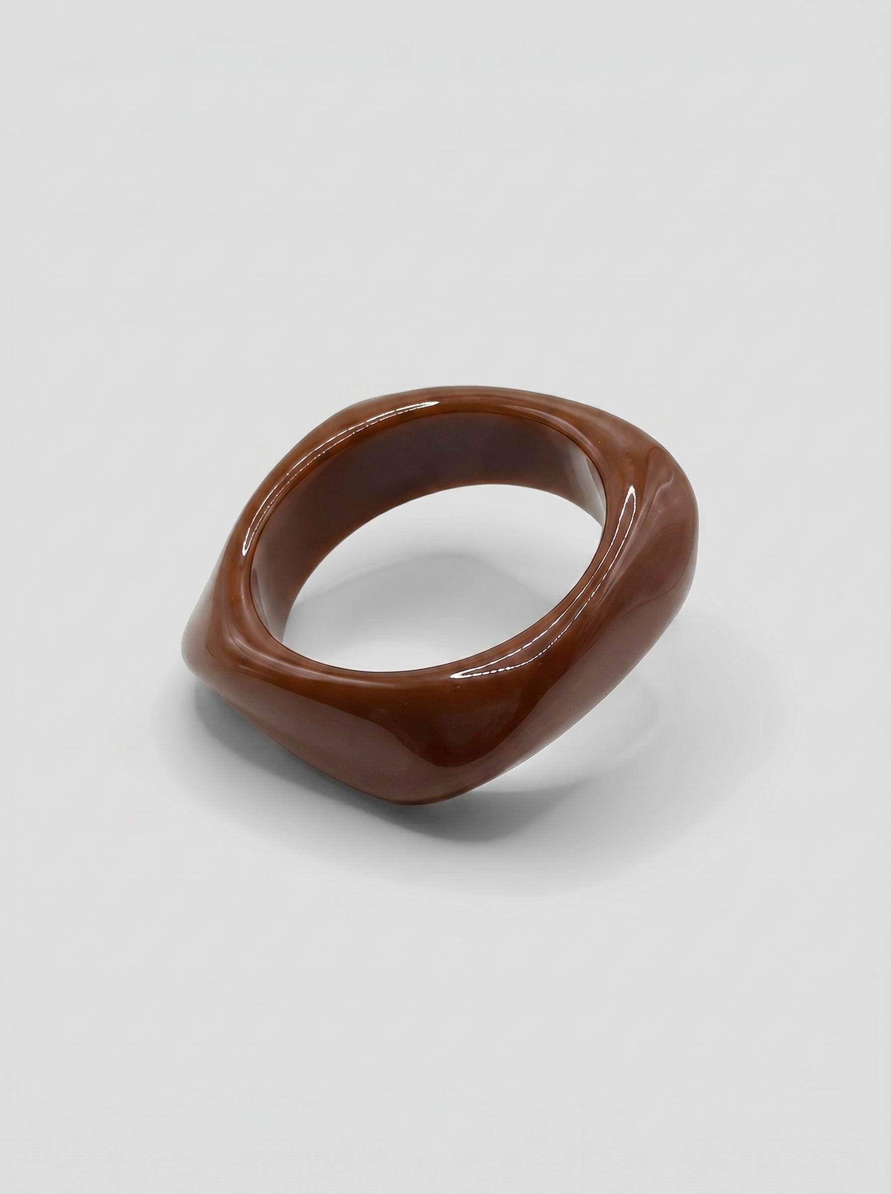 Pulseira Café em resina marmoreada nos tons café e castanho, com design orgânico geométrico e acabamento brilhante, ideal para um look elegante e contemporâneo.
