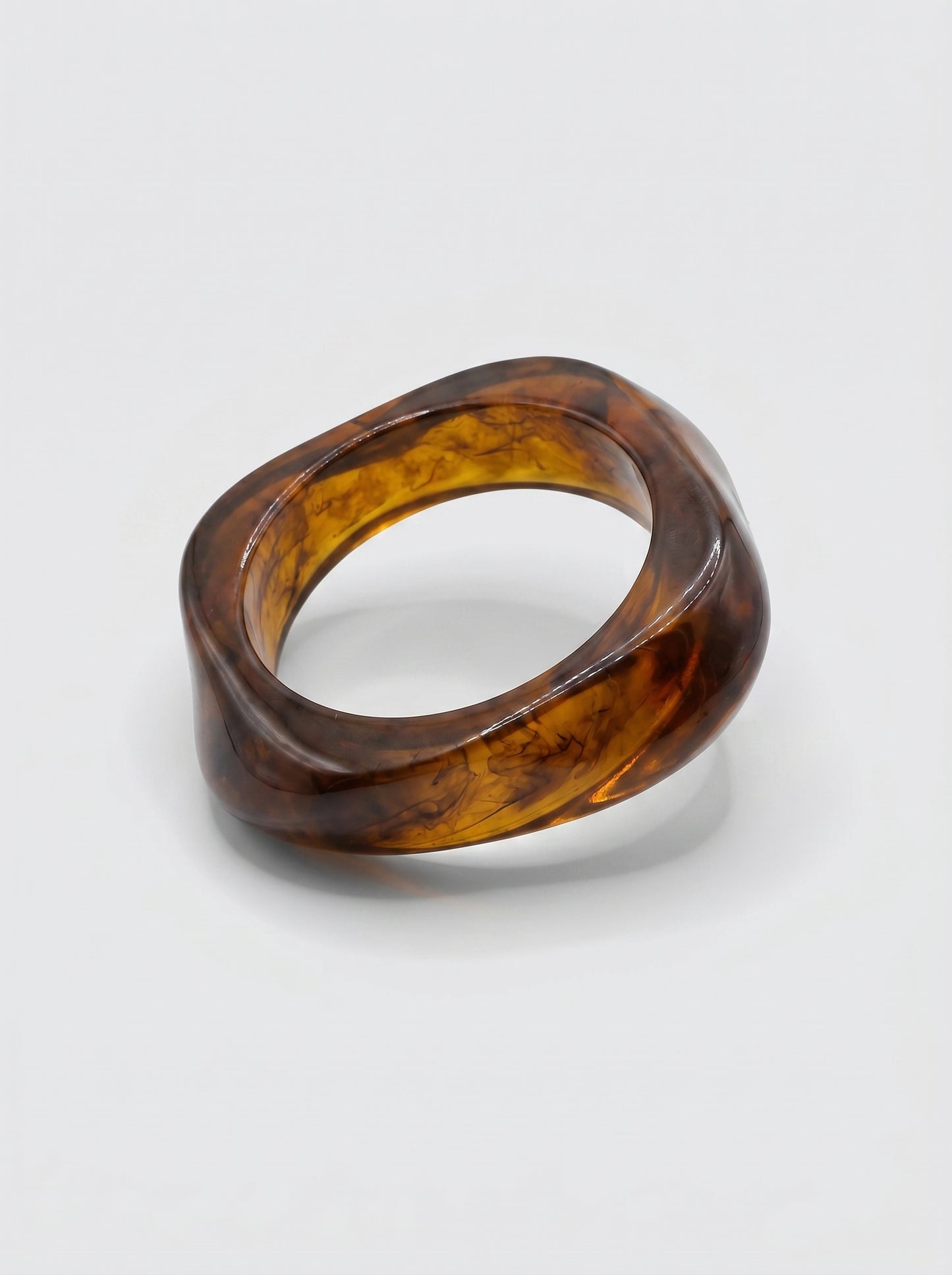 Pulseira Canela em resina marmoreada nos tons canela e âmbar escuro, com design orgânico geométrico e acabamento brilhante, ideal para um look elegante e contemporâneo.
