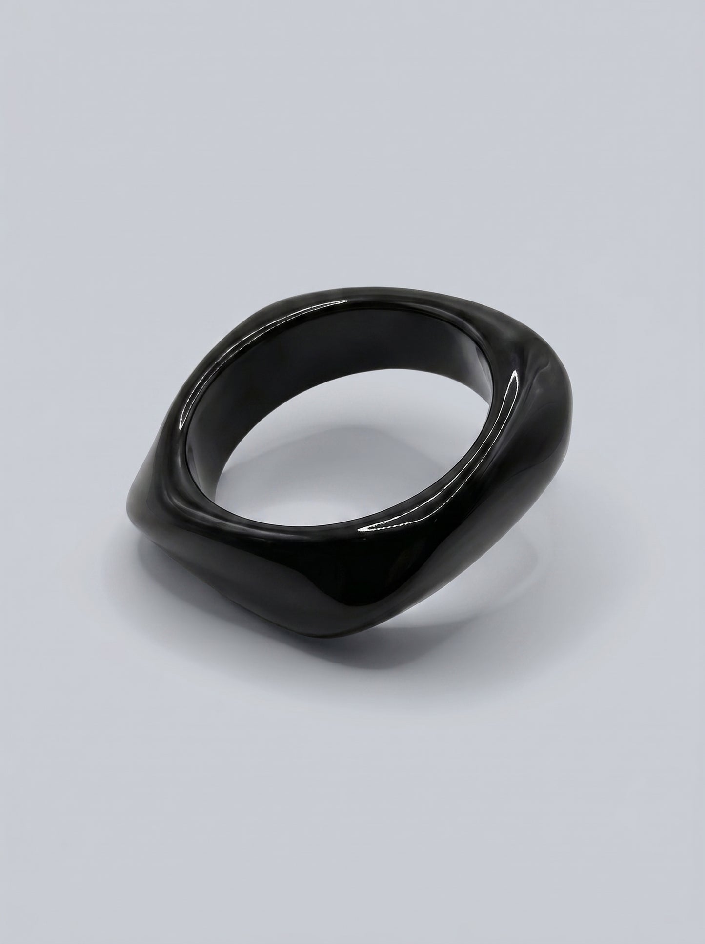 Pulseira Carvão em resina marmoreada nos tons carvão e cinza escuro, com design orgânico geométrico e acabamento brilhante, ideal para um look elegante e contemporâneo.
