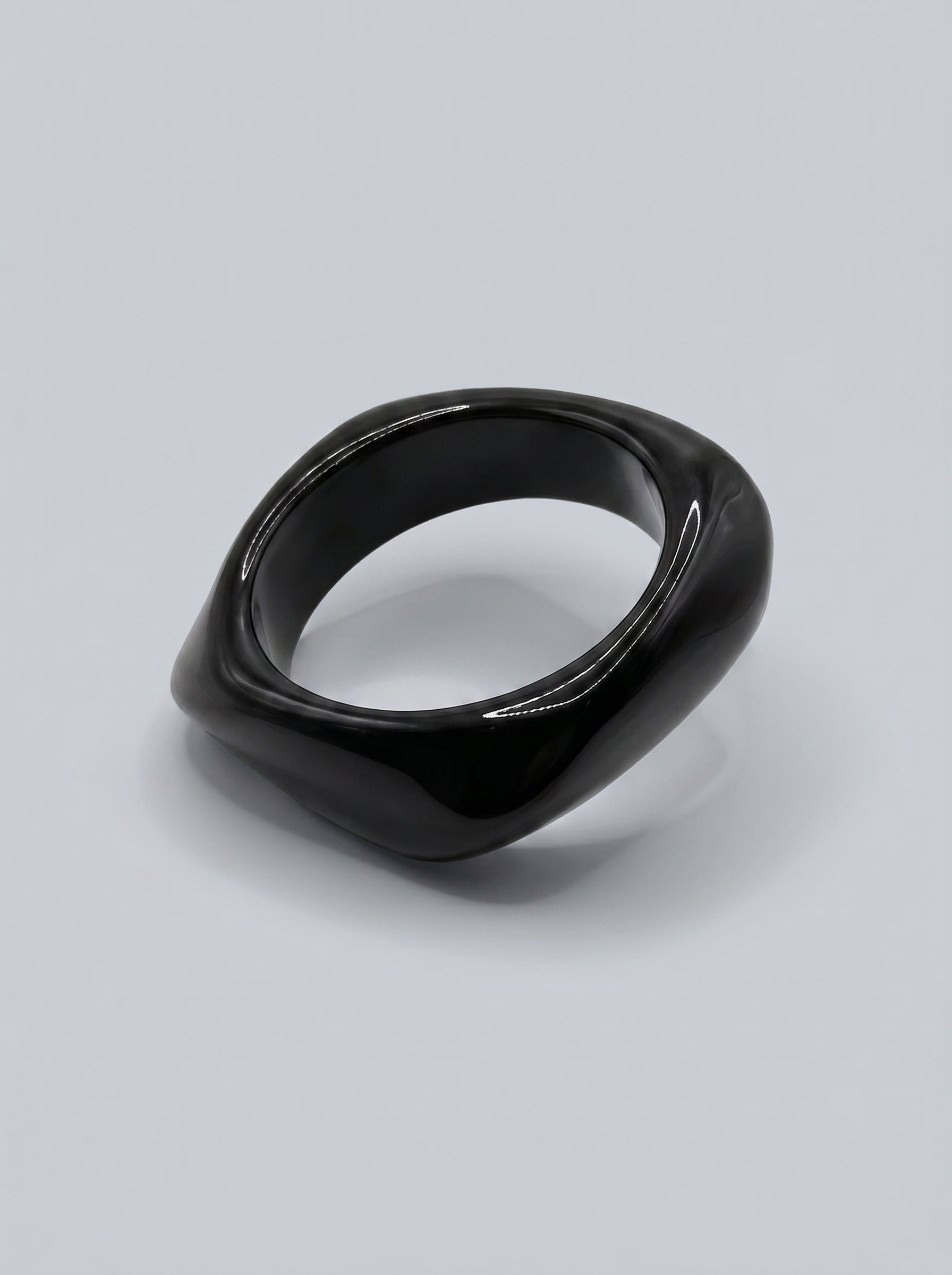 Pulseira Carvão em resina marmoreada nos tons carvão e cinza escuro, com design orgânico geométrico e acabamento brilhante, ideal para um look elegante e contemporâneo.
