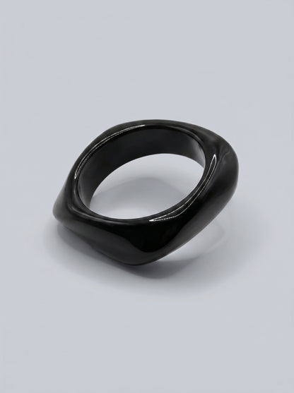 Pulseira Carvão em resina marmoreada nos tons carvão e cinza escuro, com design orgânico geométrico e acabamento brilhante, ideal para um look elegante e contemporâneo.

