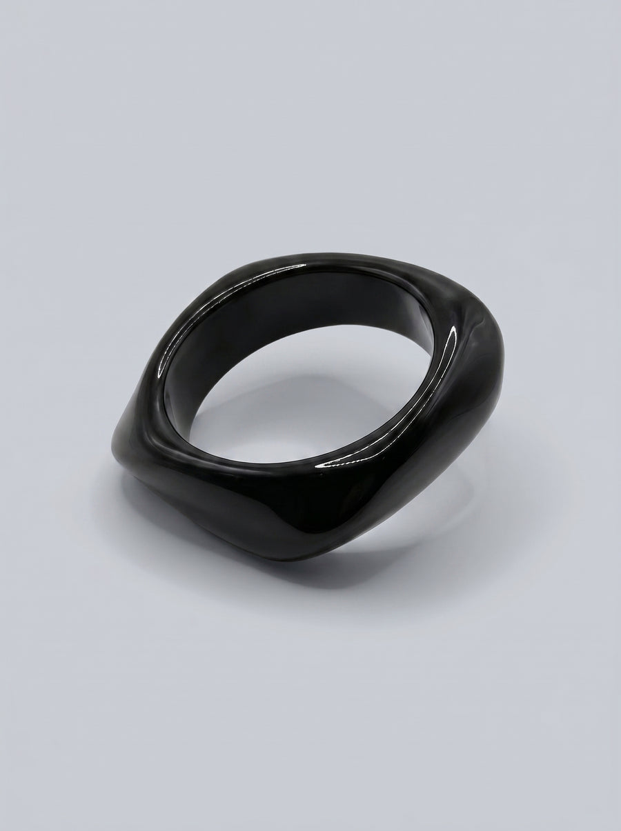 Pulseira Carvão em resina marmoreada nos tons carvão e cinza escuro, com design orgânico geométrico e acabamento brilhante, ideal para um look elegante e contemporâneo.
