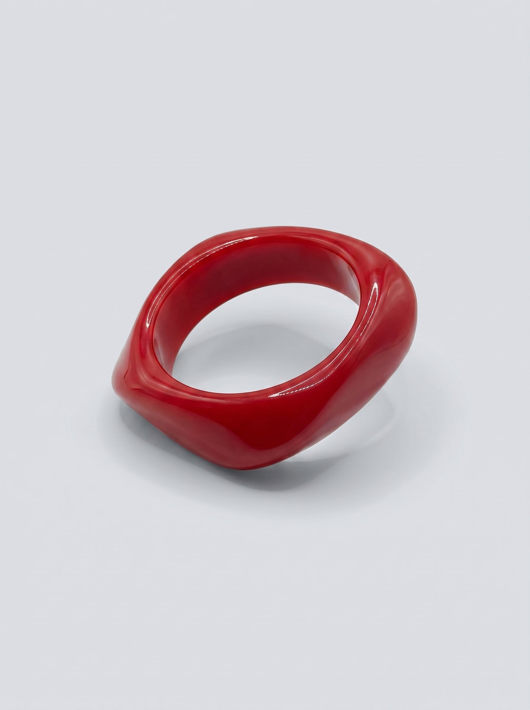 Pulseira Cereja em resina marmoreada nos tons cereja e vermelho profundo, com design orgânico geométrico e acabamento brilhante, ideal para um look elegante e contemporâneo.
