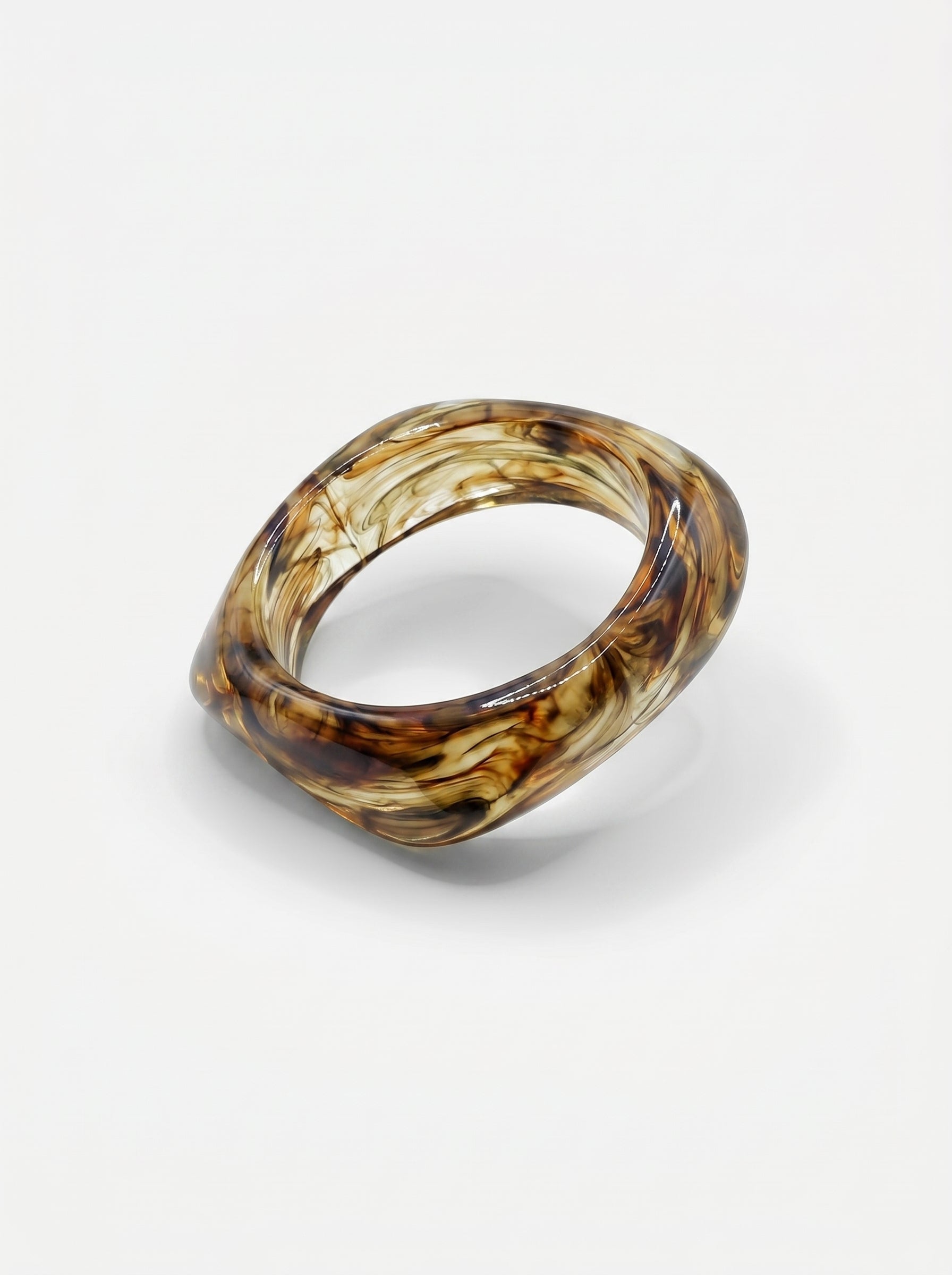 Pulseira de resina castanha marmoreada, com formato retangular e acabamento brilhante.