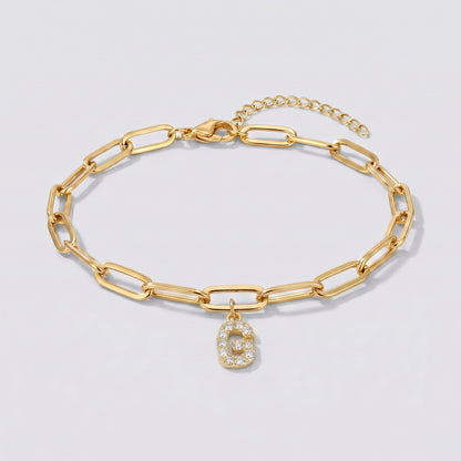 Pulseira dourada com letra inicial G, corrente paperclip e pendente de letra cravejado.