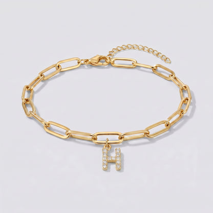 Pulseira dourada com letra inicial H, corrente paperclip e pendente de letra cravejado.