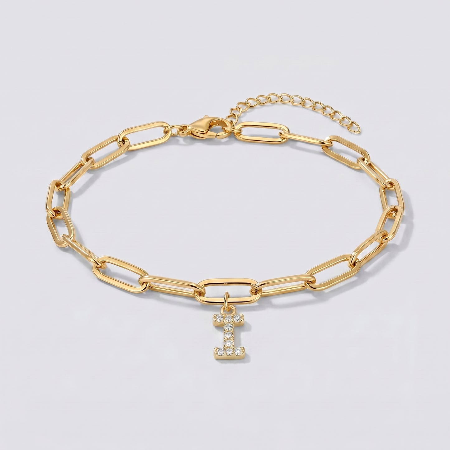 Pulseira dourada com letra inicial I, corrente paperclip e pendente de letra cravejado.
