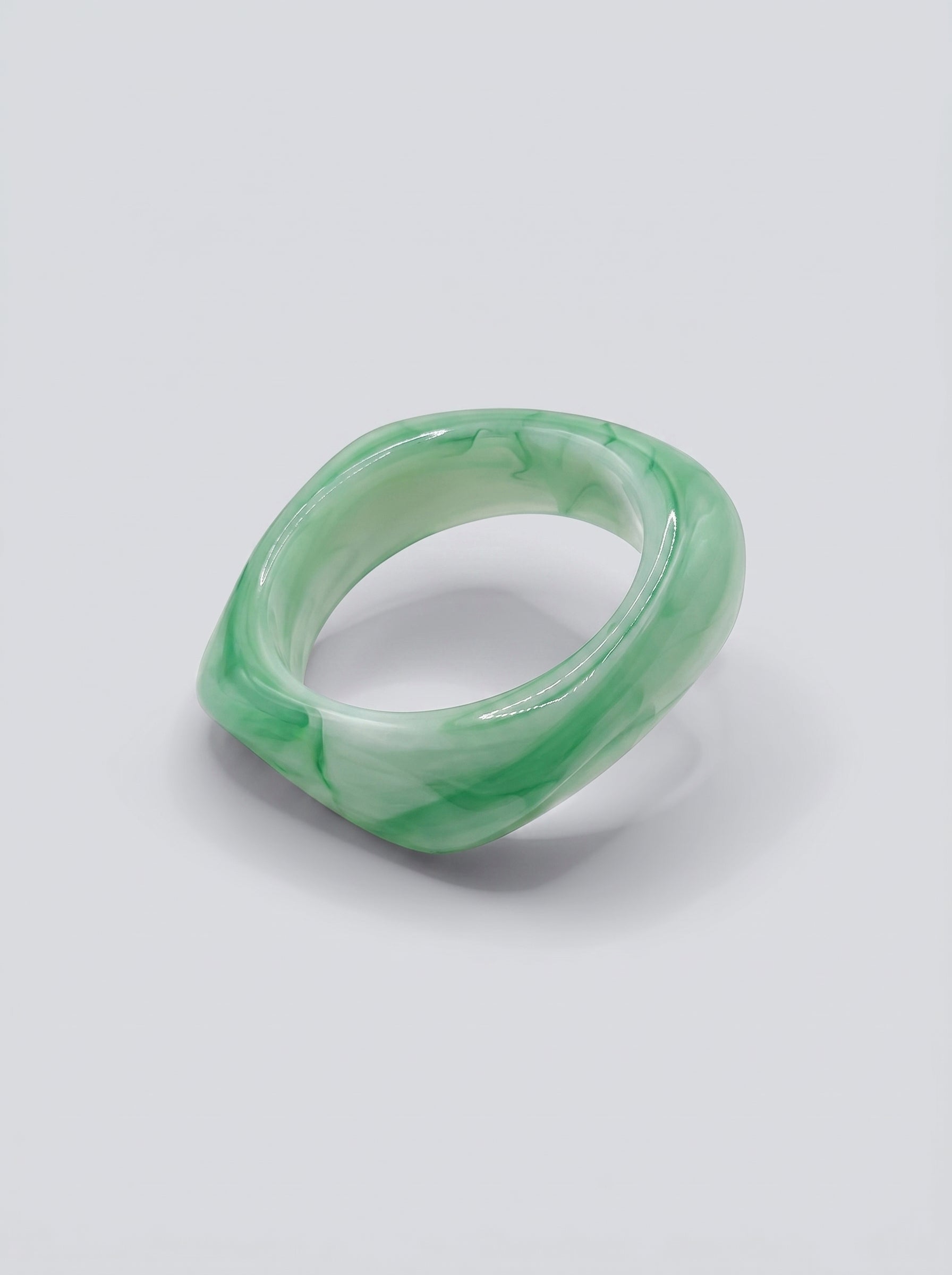 Pulseira Jade em resina marmoreada nos tons jade e verde suave, com design orgânico geométrico e acabamento brilhante, ideal para um look elegante e contemporâneo.
