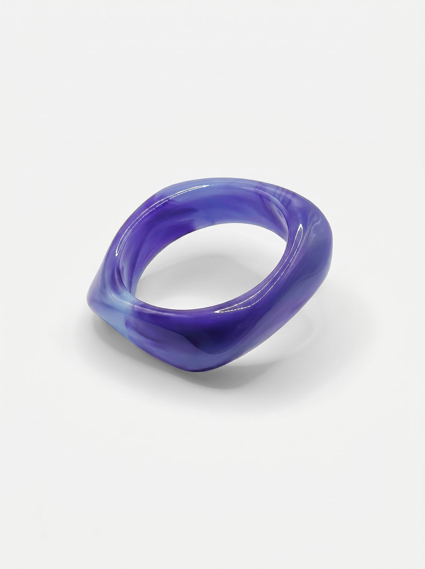 Pulseira Lavanda em resina marmoreada nos tons lavanda e lilás, com design orgânico geométrico e acabamento brilhante, ideal para um look elegante e contemporâneo.
