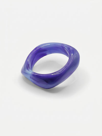 Pulseira Lavanda em resina marmoreada nos tons lavanda e lilás, com design orgânico geométrico e acabamento brilhante, ideal para um look elegante e contemporâneo.
