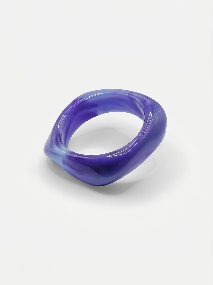 Pulseira Lavanda em resina marmoreada nos tons lavanda e lilás, com design orgânico geométrico e acabamento brilhante, ideal para um look elegante e contemporâneo.
