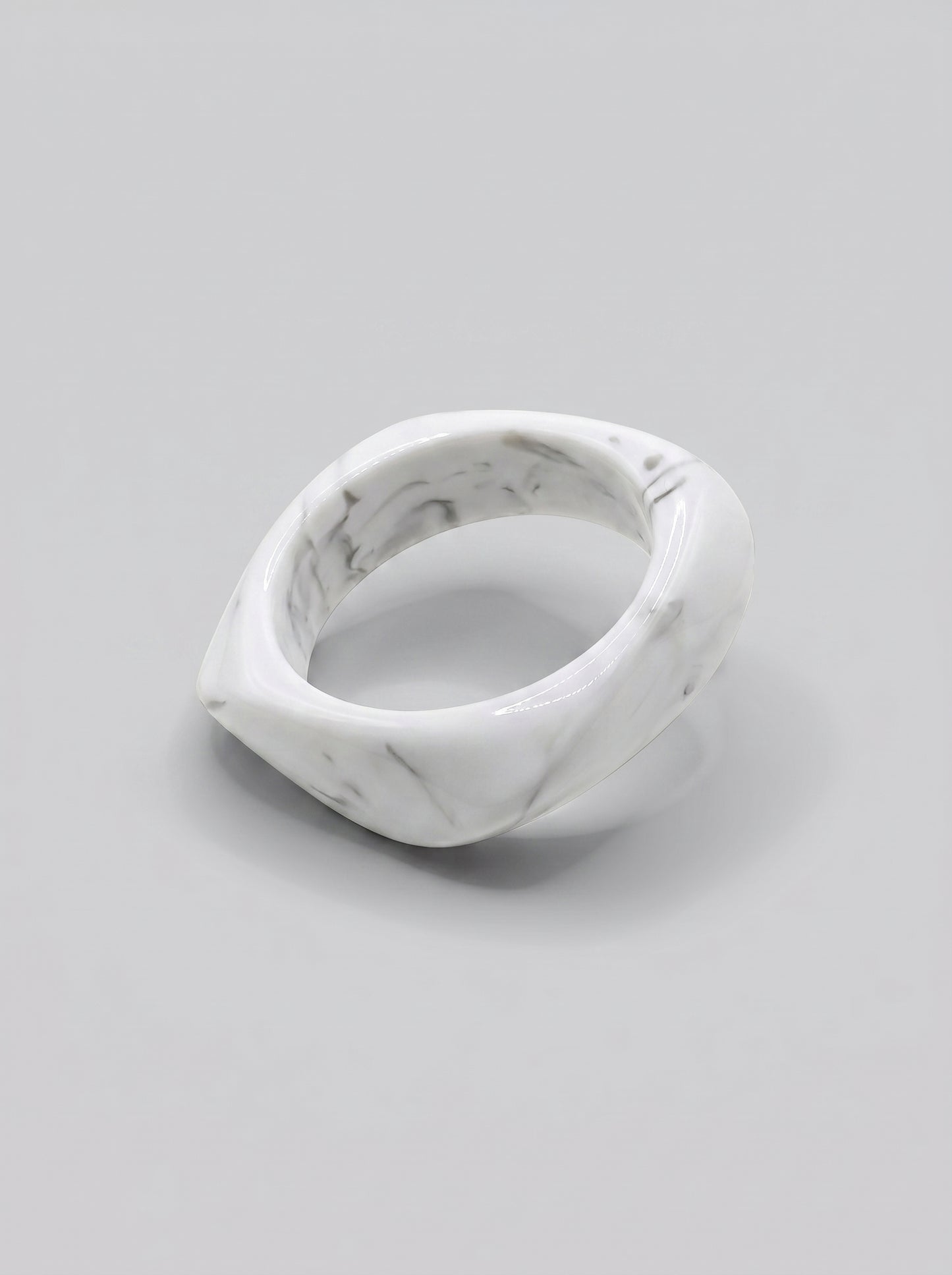 Pulseira Mármore em resina marmoreada nos tons mármore branco e cinza, com design orgânico geométrico e acabamento brilhante, ideal para um look elegante e contemporâneo.
