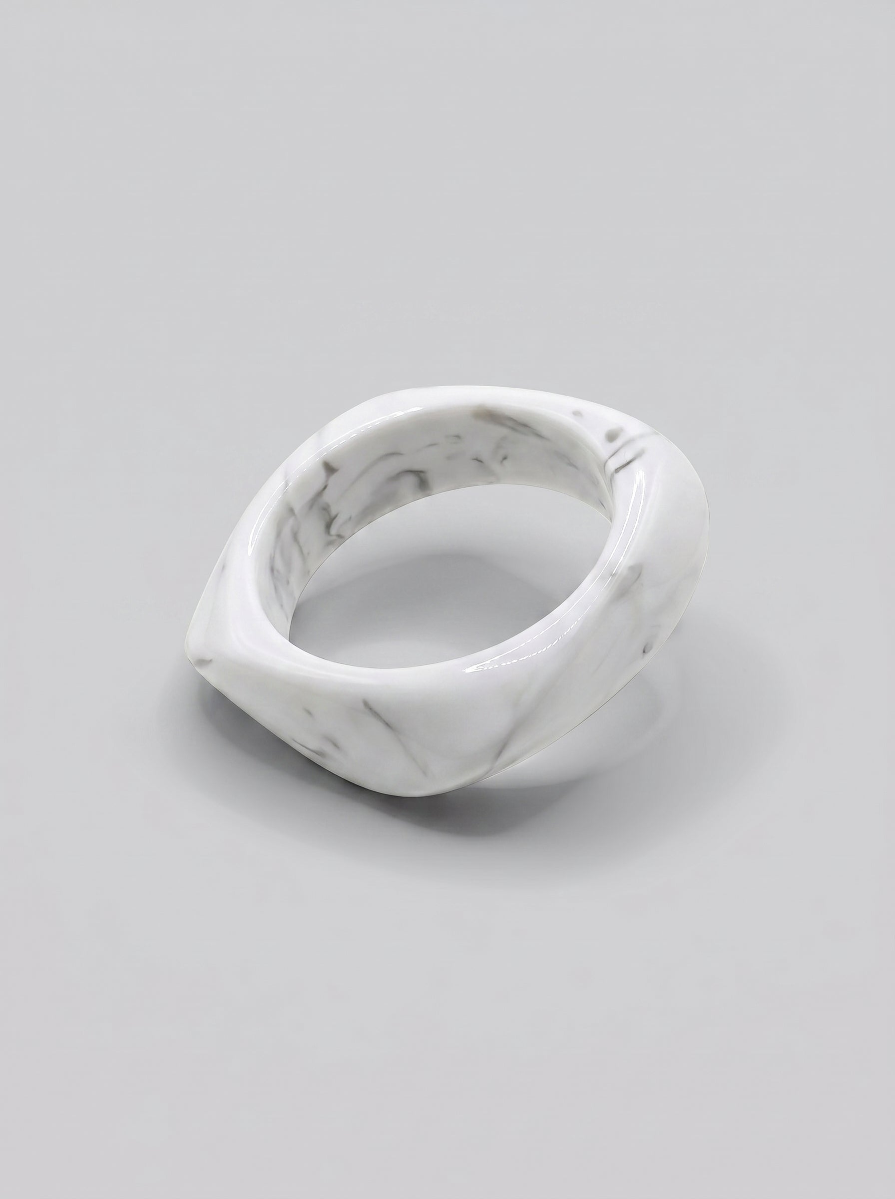 Pulseira Mármore em resina marmoreada nos tons mármore branco e cinza, com design orgânico geométrico e acabamento brilhante, ideal para um look elegante e contemporâneo.
