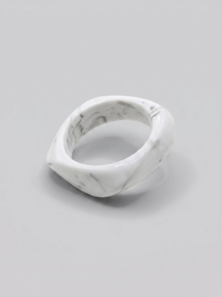 Pulseira Mármore em resina marmoreada nos tons mármore branco e cinza, com design orgânico geométrico e acabamento brilhante, ideal para um look elegante e contemporâneo.
