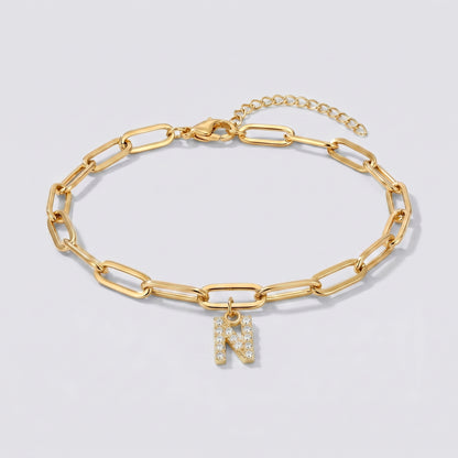 Pulseira dourada com letra inicial N, corrente paperclip e pendente de letra cravejado.