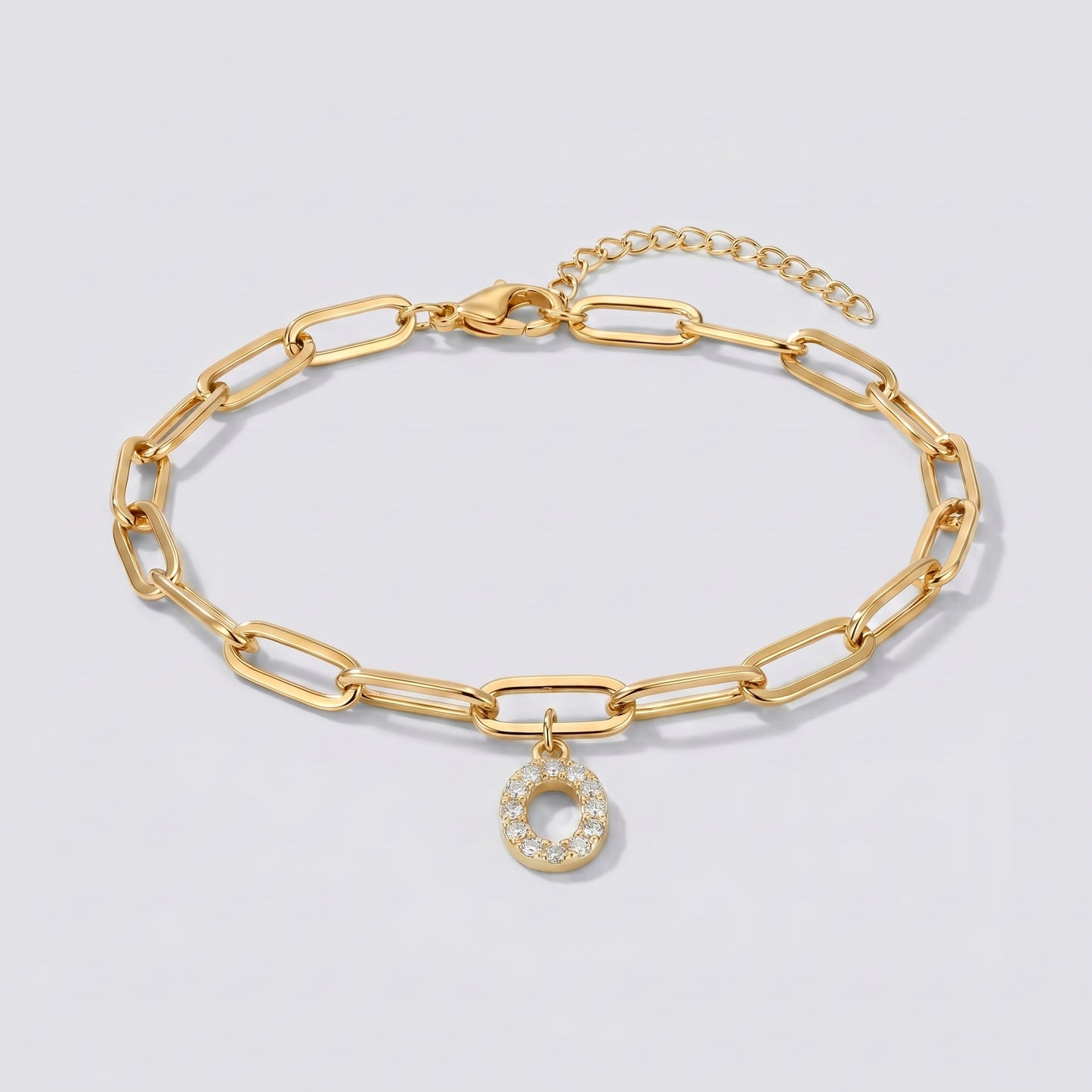 Pulseira dourada com letra inicial O, corrente paperclip e pendente de letra cravejado.