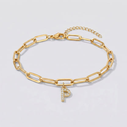 Pulseira dourada com letra inicial P, corrente paperclip e pendente de letra cravejado.