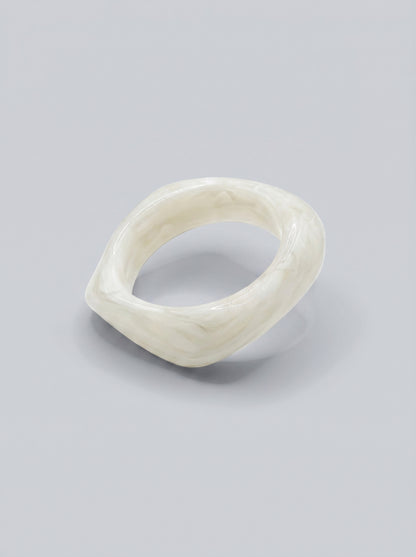 Pulseira Pérola em resina marmoreada branca, com design orgânico geométrico e acabamento brilhante, ideal para um look elegante e contemporâneo.