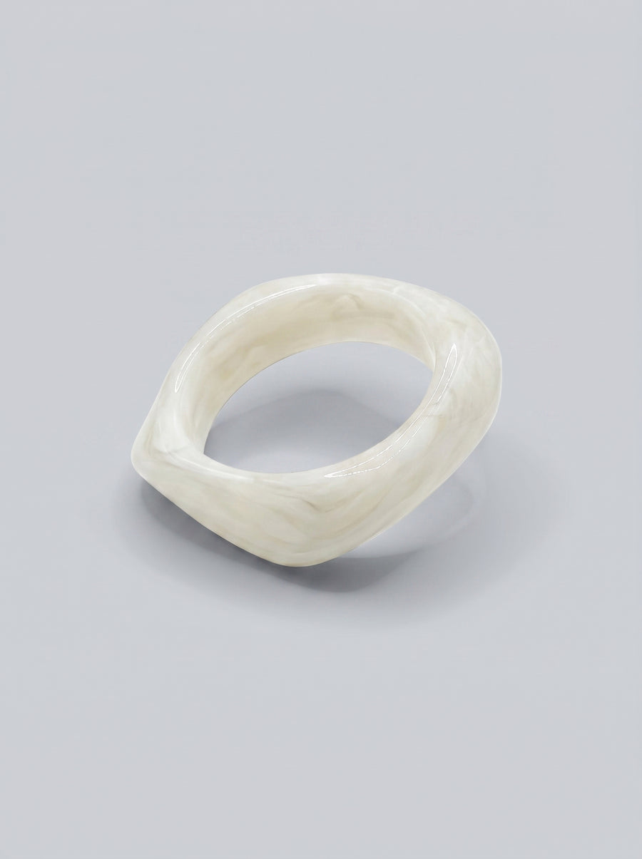 Pulseira Pérola em resina marmoreada branca, com design orgânico geométrico e acabamento brilhante, ideal para um look elegante e contemporâneo.