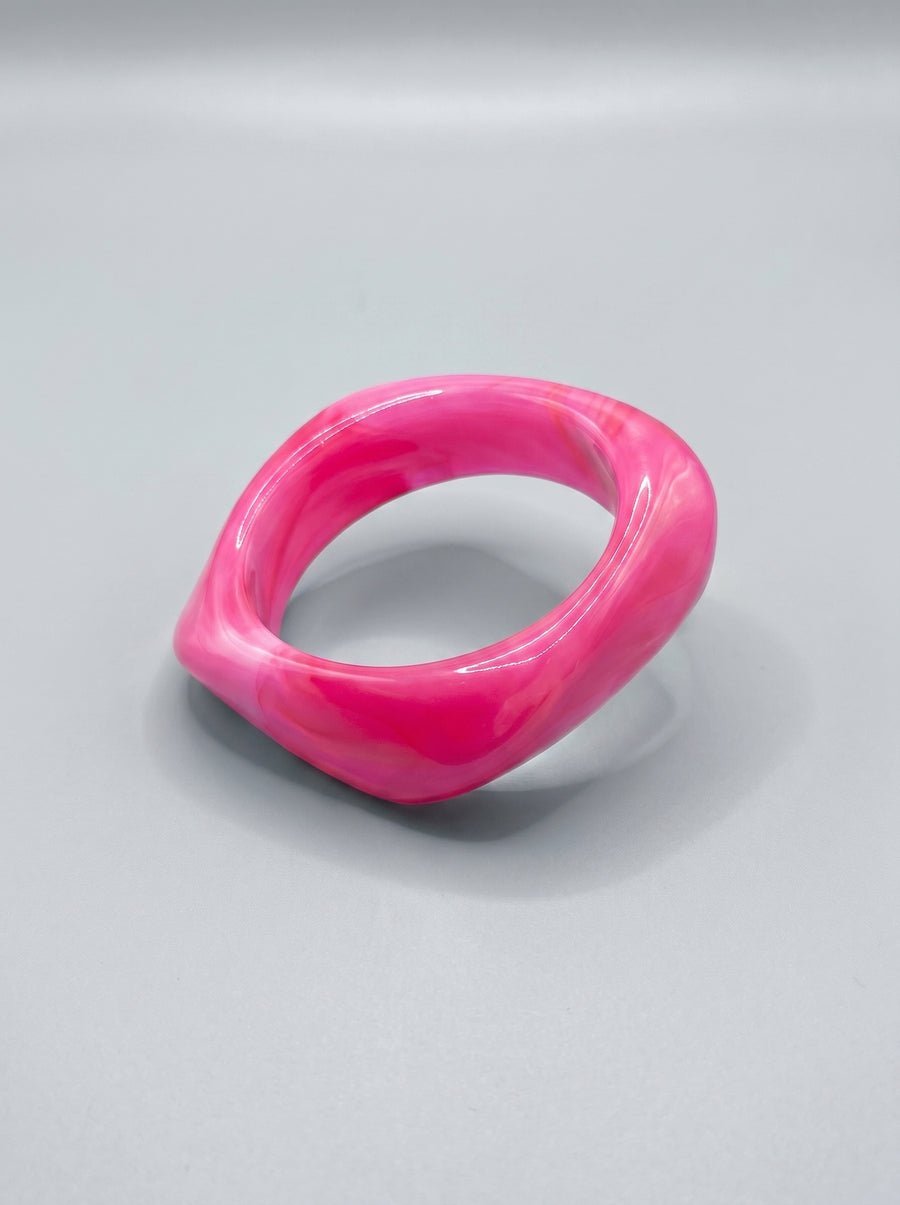 Pulseira de resina rosa marmoreada, com formato retangular e acabamento brilhante.